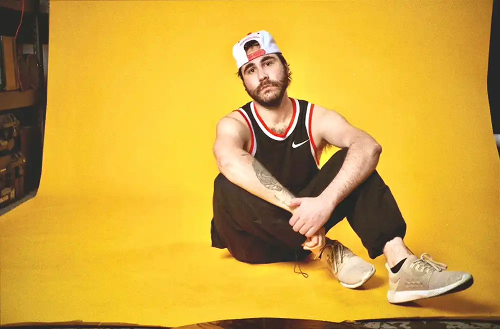 DMGD posing in front of a vibrant yellow-orange backdrop during a photoshoot.