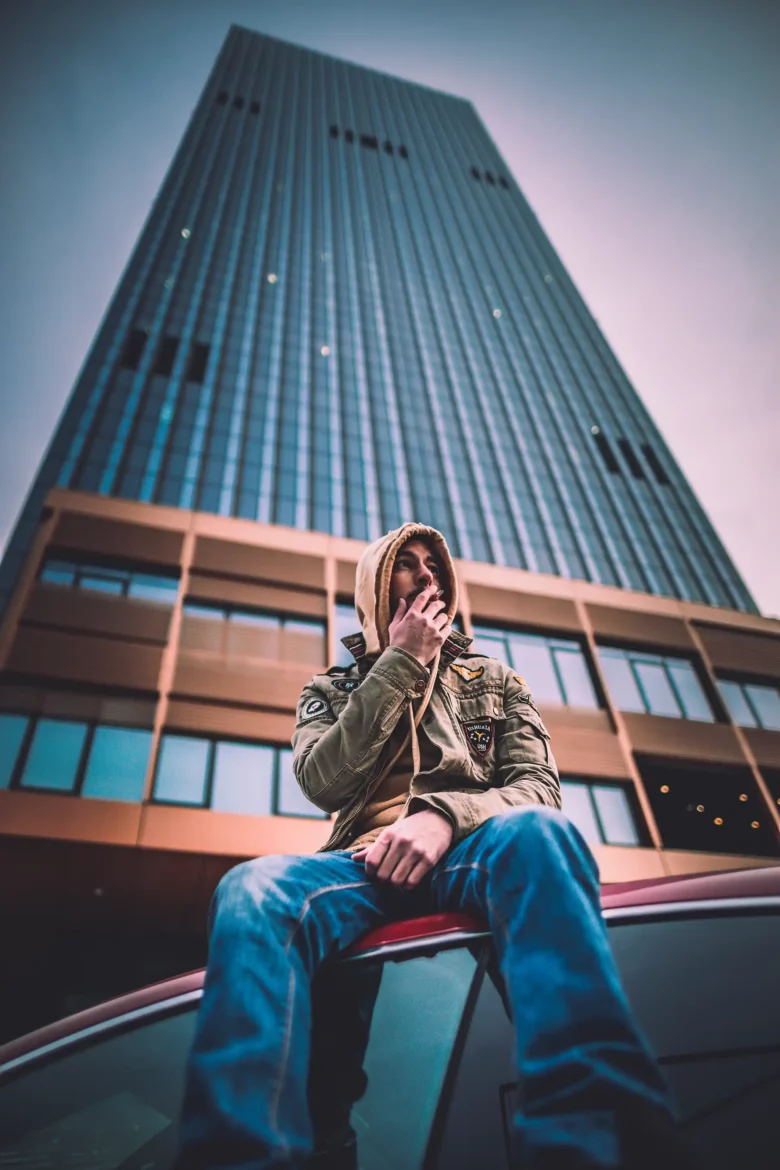 Capo Beatz posing in front of an urban office tower during a captivating photoshoot.