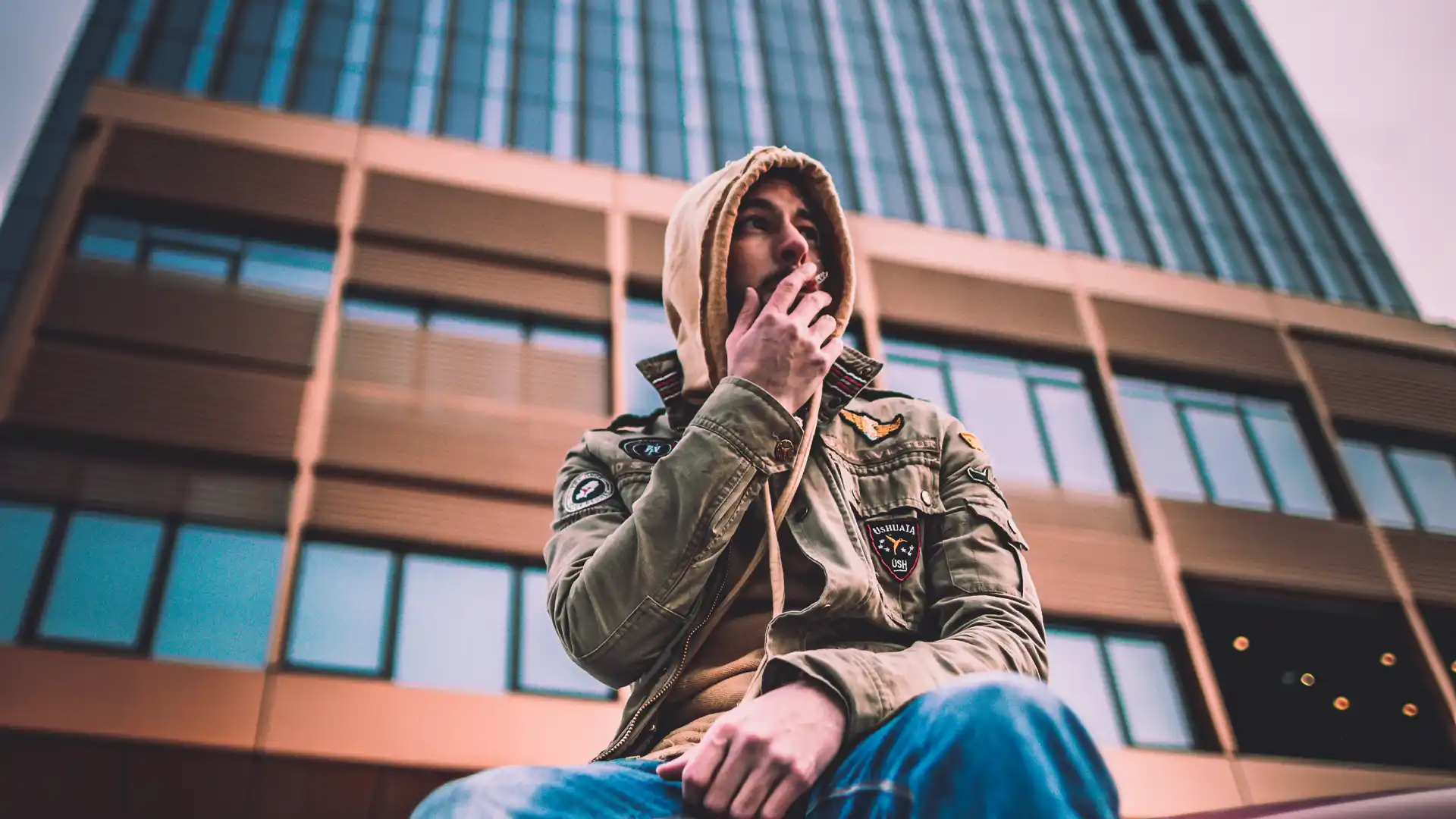 Capo Beatz posing in front of an urban office tower during a captivating photoshoot.