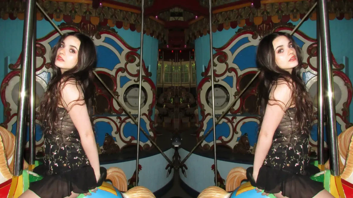 Mirrored image of Kiki Kramer, capturing her sensual side while riding an amusement ride.