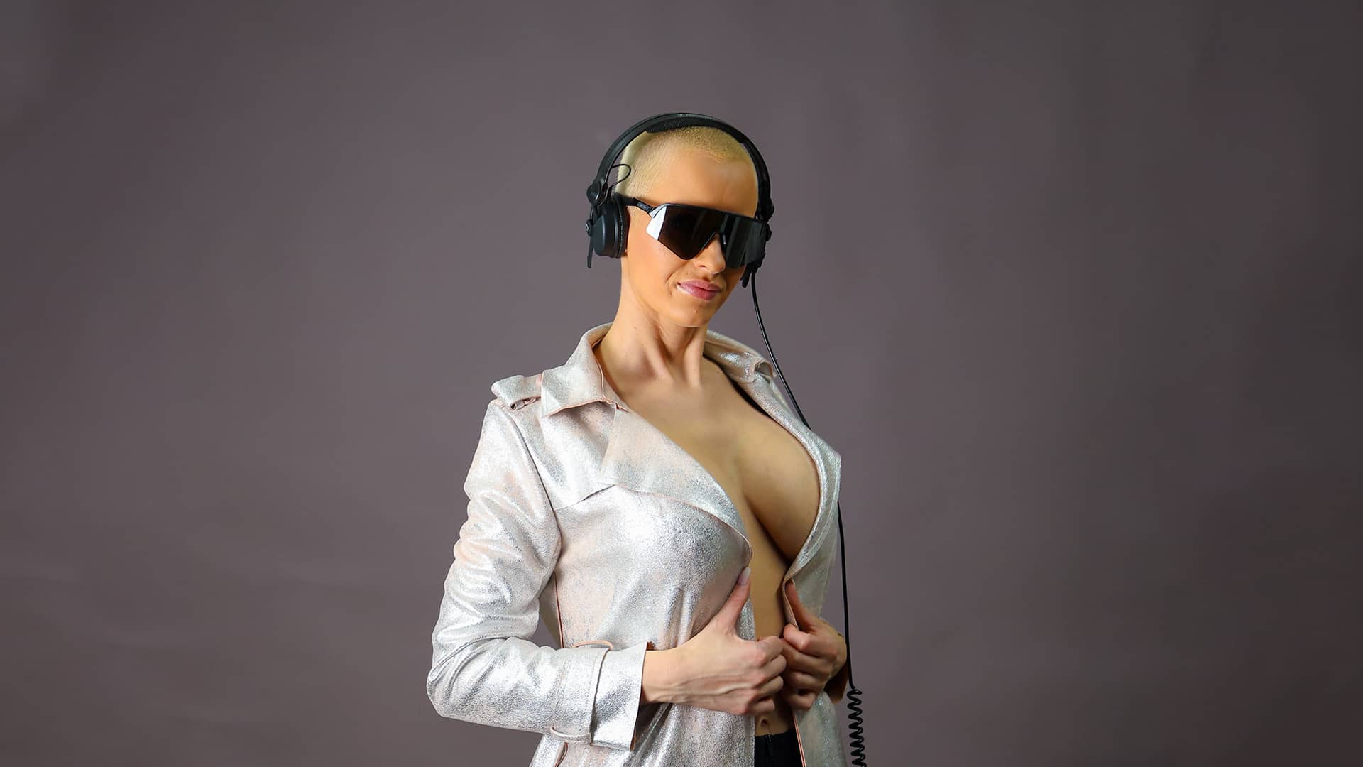 Anike Ekina standing behind a DJ desk with sunglasses and a headset.