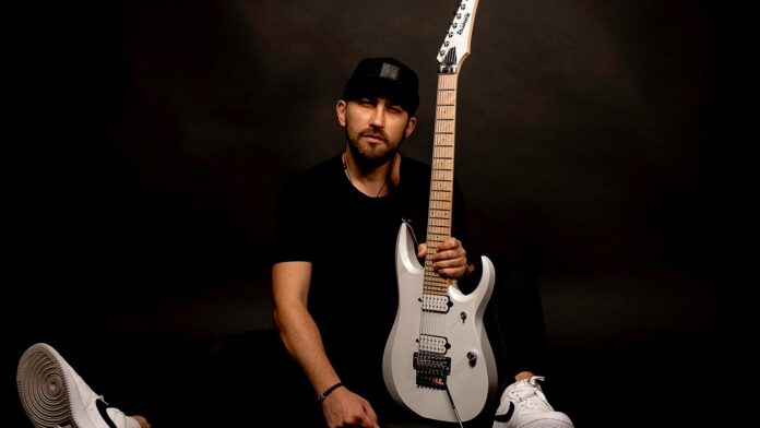 Cevret in black attire with a white electric guitar