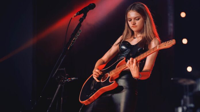 Sierra Levesque performs on stage with her guitar.