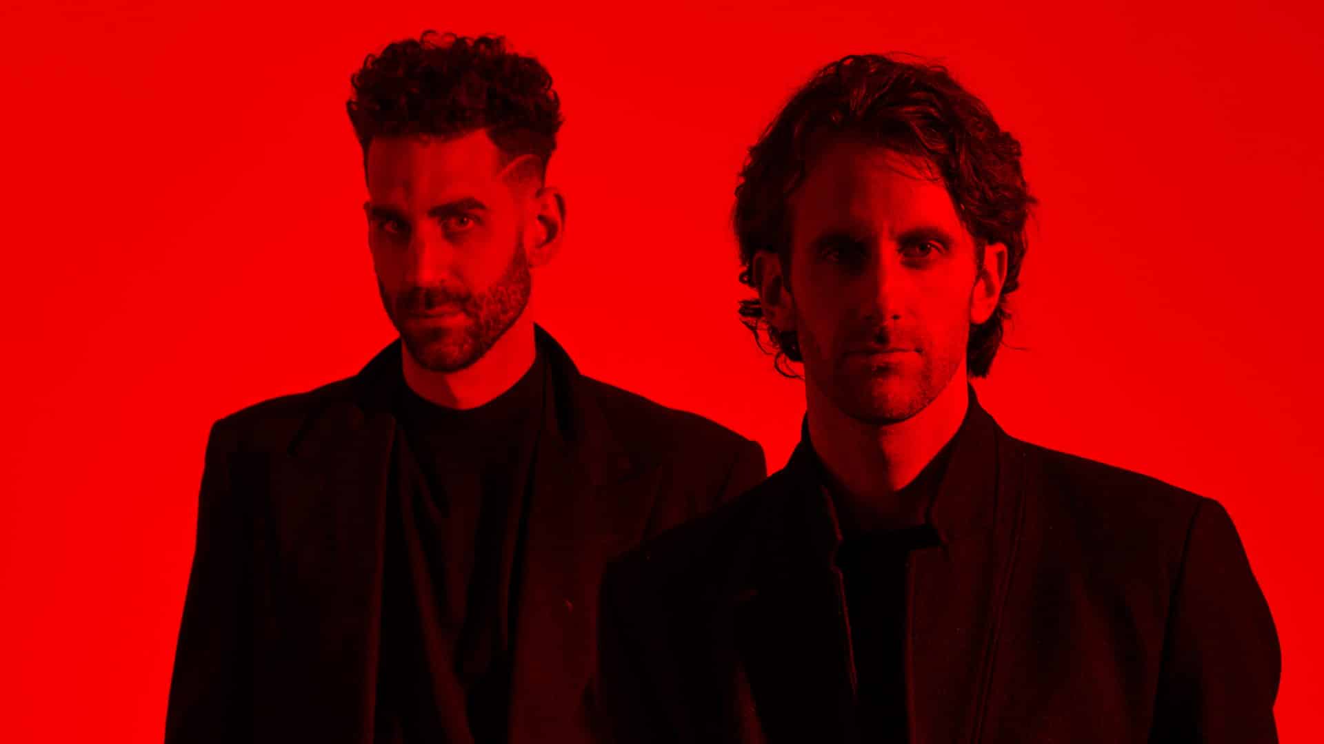 The Listros stand against a vivid red background, exuding a cool confidence in black attire.