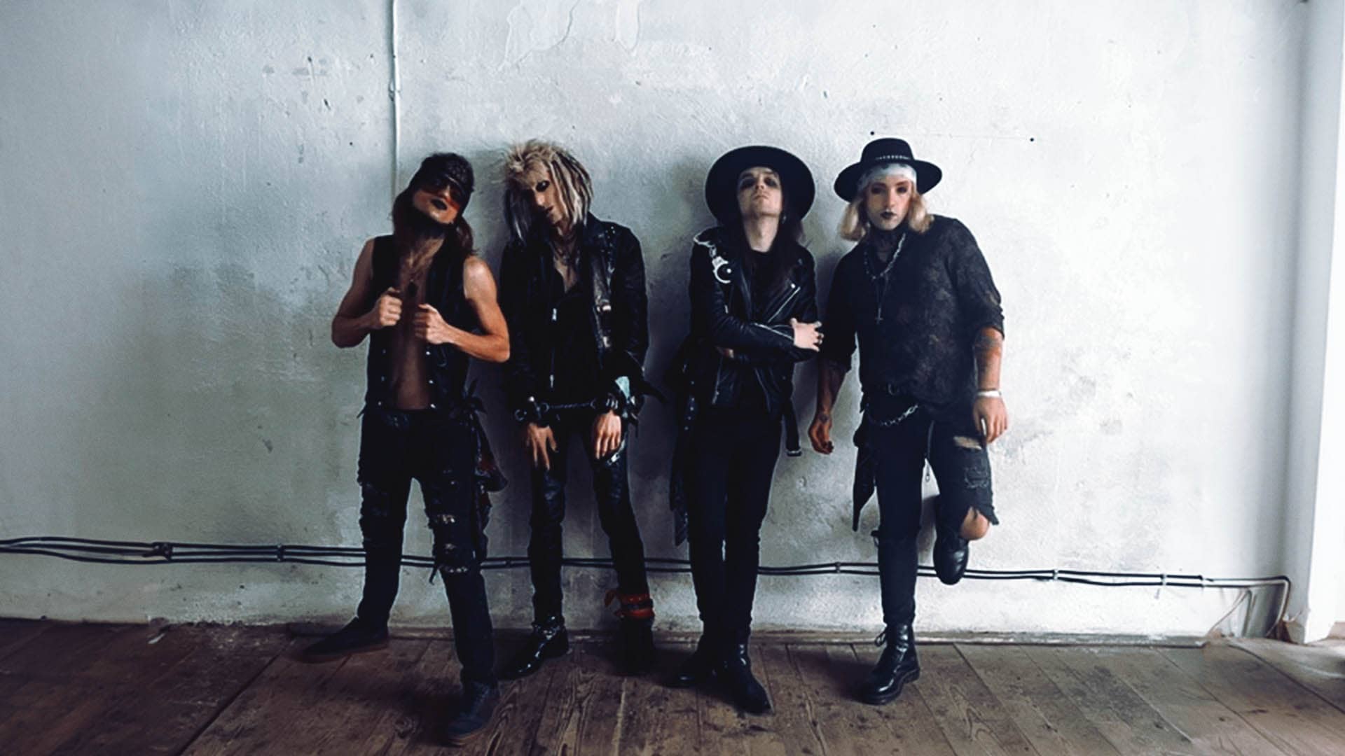 Band Wildstreet posing against a white wall in rock attire for 